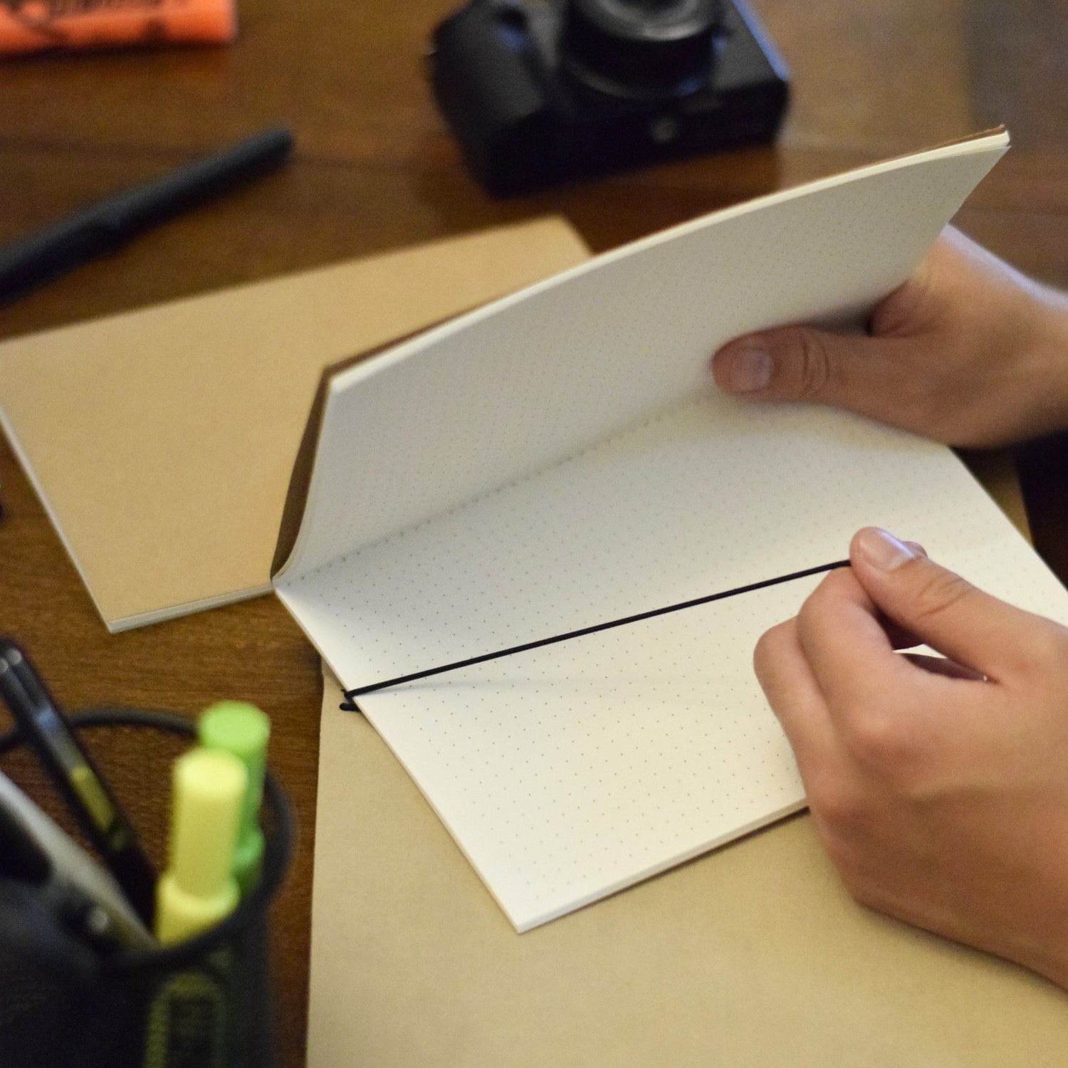 Action shot of the Uprise Notebook showing the elastic band being lifted as a modular insert is removed, demonstrating the customizable and flexible design. Perfect for individual with busy lifestyle, students, artists and creatives alike.