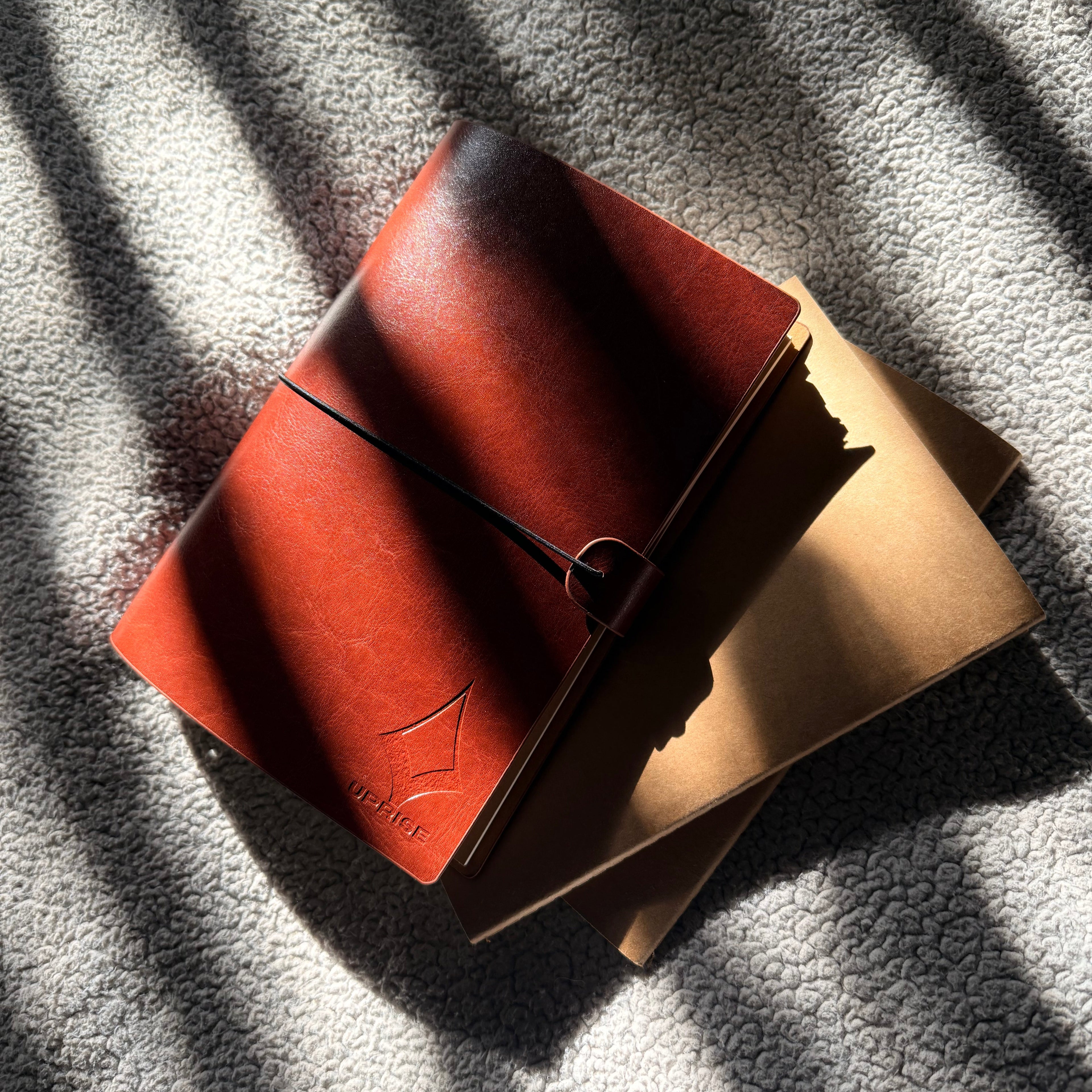 Earth brown Uprise Notebook with premium vegan leather cover displayed under natural sunlight, showcasing customizable modular inserts for planning, journaling, and productivity.