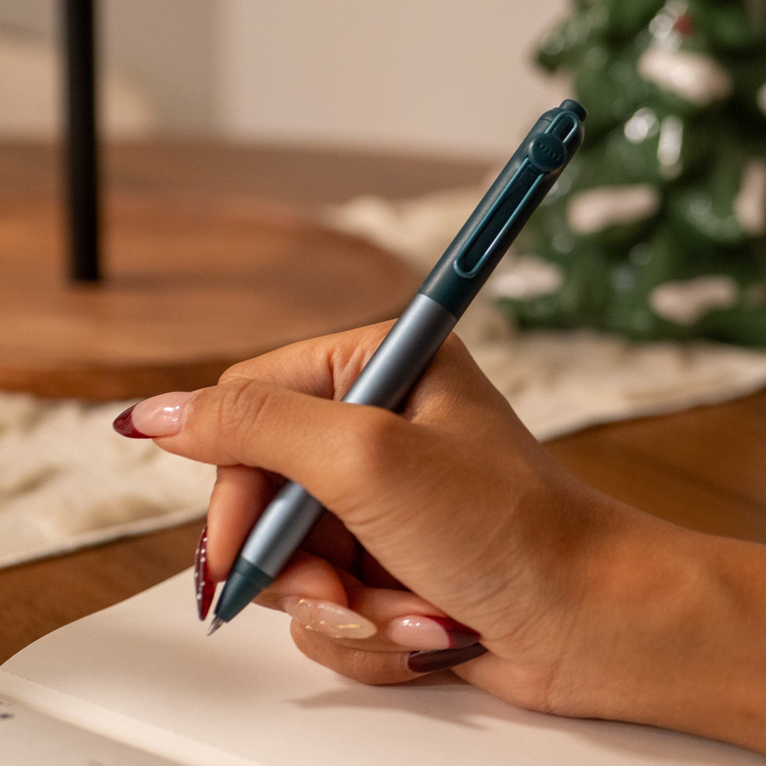 Hand holding a Zento Flow Gel pen over a Uprise Notebook