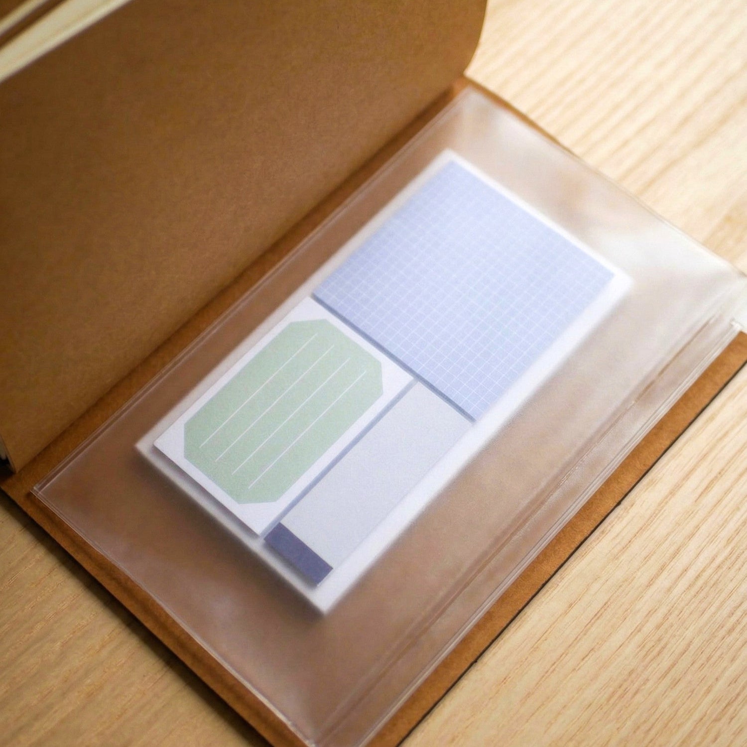 Set of sticky notes in a clear plastic case on a wooden surface