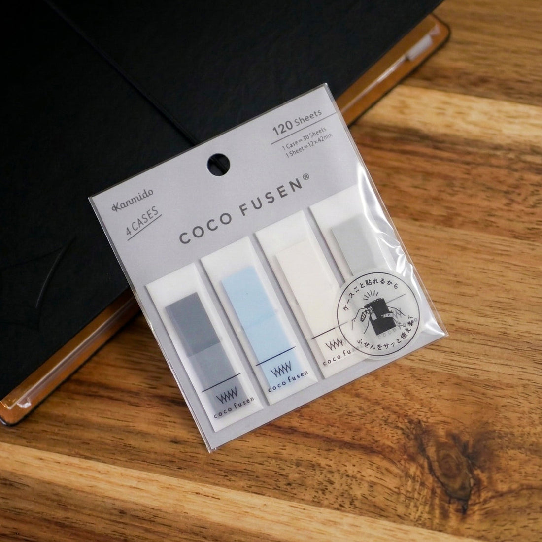 Coco Fusen sticky notes on top of a black Uprise Notebook on top of a wooden counter.